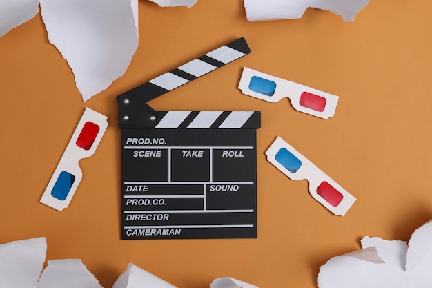 Movie clapboard with 3d glasses and torn paper sheets on beige background Top view