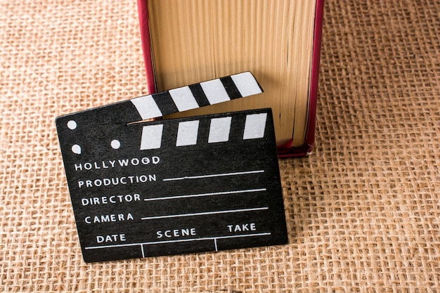 Photo movie clapper beside a book on a canvas background