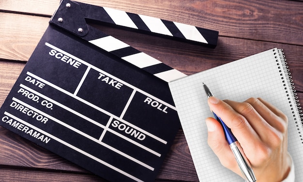 Movie clapper board and film tapes on wooden background