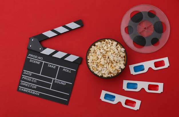 Movie clapper board, popcorn bowl, 3d glasses, film reel on red background. Entertainment industry. Top view. Flat lay