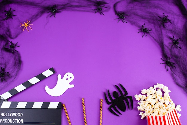 Movie clapper board in spider webs spiders ghost eyes on purple lilac background