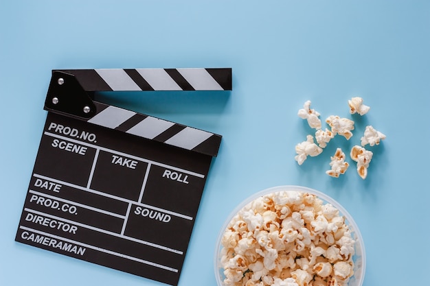 Movie clapper board with popcorn on blue background for entertainment 