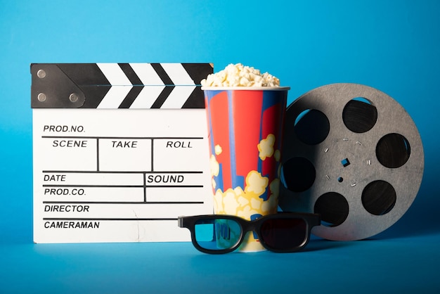 Photo movie clapper pop corn 3d glasses and film reel on blue background collage design