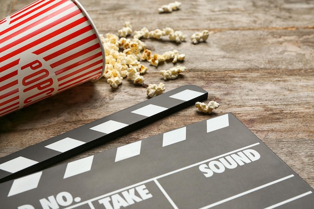 Movie clapper and popcorn on wooden background closeup