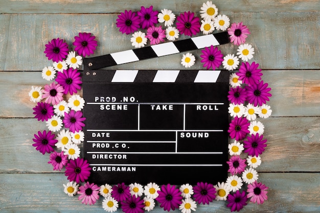Movie clapper with flowers in blue wooden surface