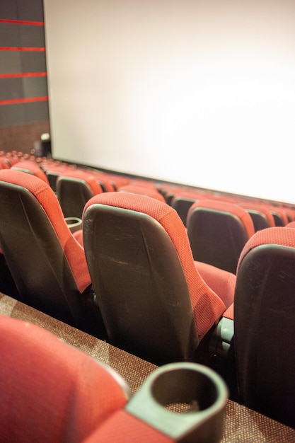 A movie theater with red seats and a white screen