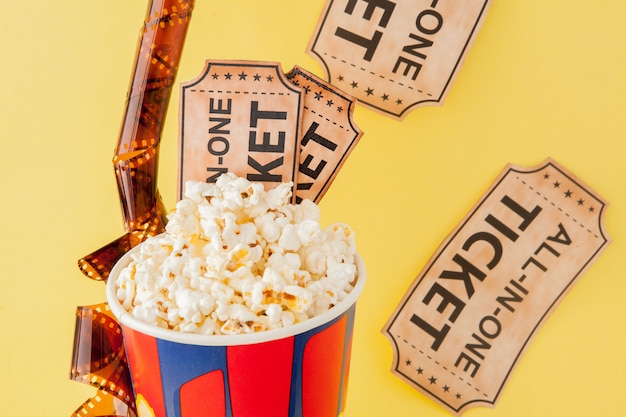 Biglietti del cinema, strisce di pellicola e popcorn sul blu