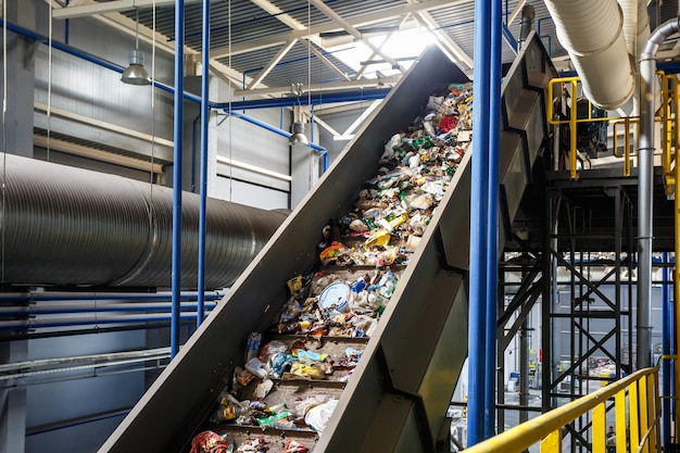 Photo moving conveyor transporter on modern waste recycling processing plant separate and sorting garbage collection recycling and storage of waste for further disposal