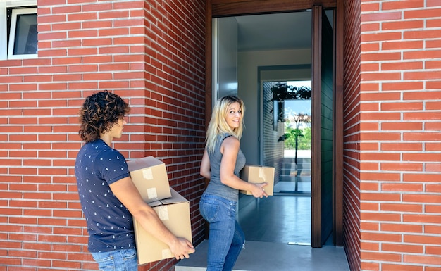 Moving couple carrying boxes to their new home