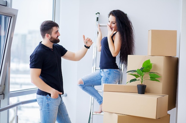 Moving day. Happy young couple carrying boxes.