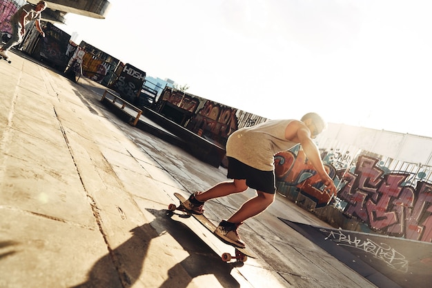 Foto muoversi velocemente. per tutta la lunghezza di due giovani uomini che fanno skateboard mentre escono allo skate park all'aperto