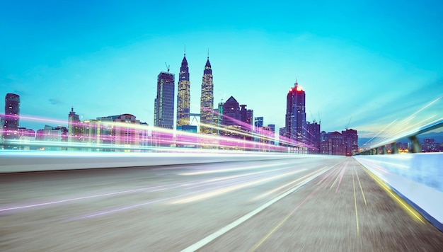 Moving forward motion blur asphalt road on night scene near the modern city with light trail