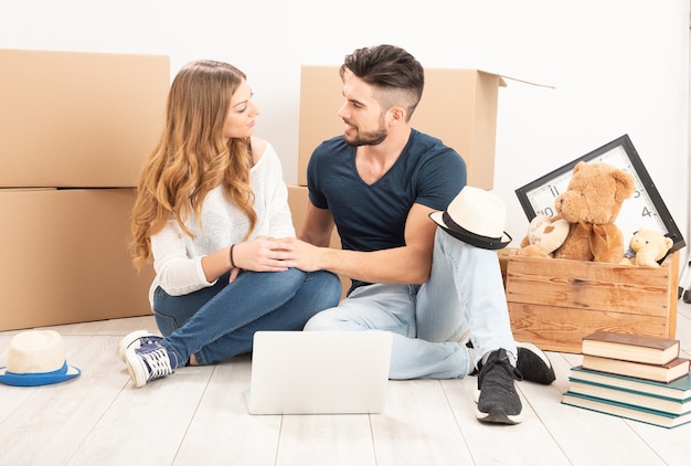 Moving Home. Couple sitting on the floor in a new house close up