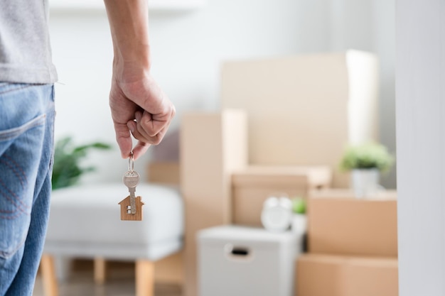 Moving house relocation Man hold key house keychain in new apartment inside the room