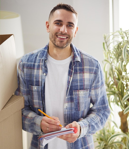 A moving man sitting on the floor in empty apartment Among the Boxes Checking the List of Things