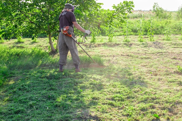 写真 草をる 庭を整える 夏の日に男がガソリンモーバーで庭で草をります