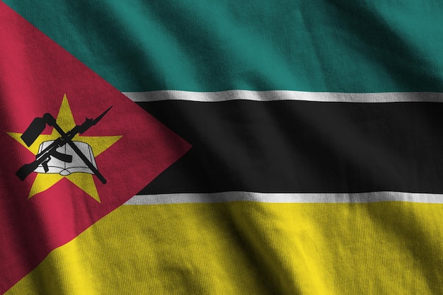 Mozambique flag with big folds waving close up under the studio light indoors The official symbols and colors in banner