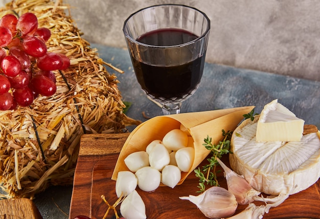 Mozzarella baby, Brie kaas met knoflook en druiven en glas wijn op houten voet