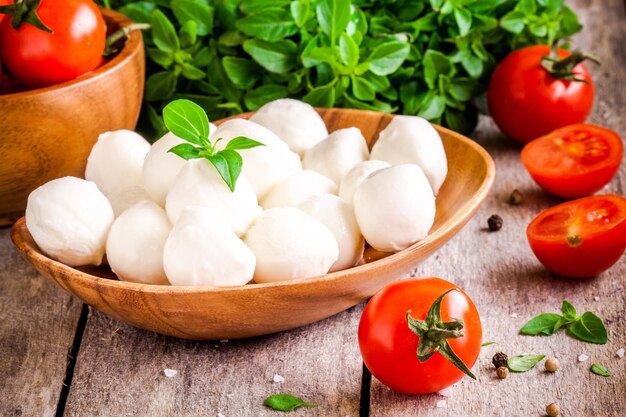 Mozzarella biologische kerstomaatjes en verse basilicum op een rustieke houten achtergrond