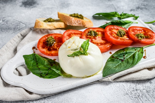 Mozzarella burrata salade met basilicumbladeren en tomaten.