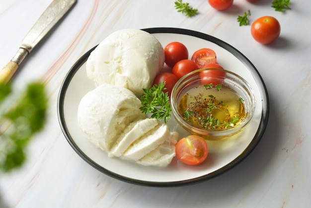 Mozzarella cheese and cherry tomatoes with spices. Homemade mozzarella cheese.