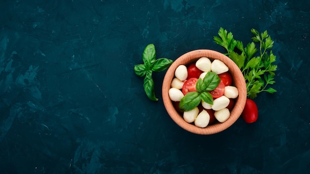 Mozzarella cheese cherry tomatoes in a wooden plate Salad caprese On a black table Free space for text