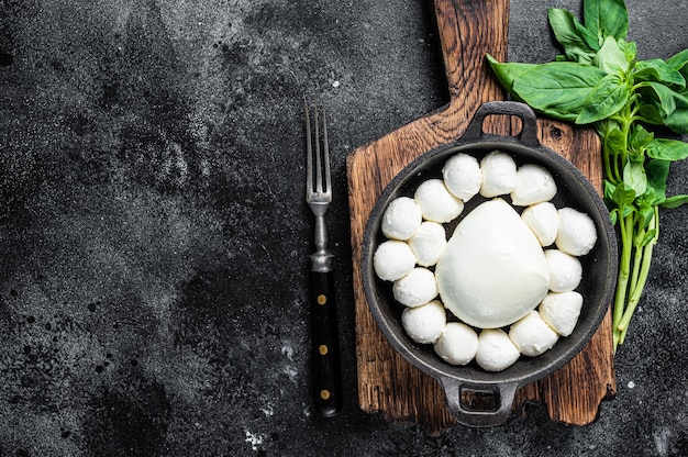 Mozzarella cheese mini balls in pan with basil.