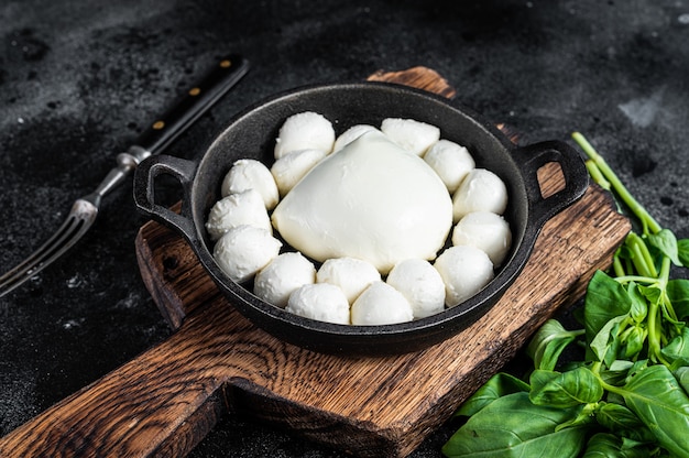 Mozzarella cheese mini balls in pan with basil.