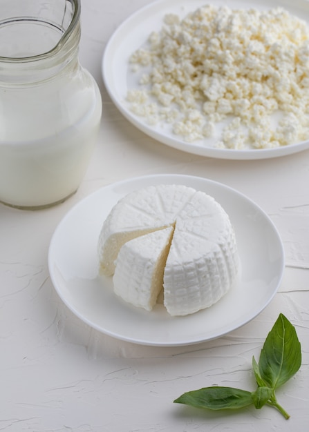 Foto mozzarella e ricotta rotonda con latte su fondo bianco.