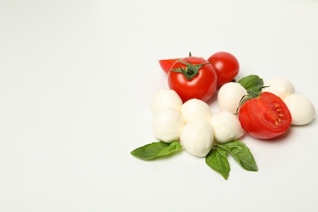 Mozzarella cheese, tomato and basil on white background, space for text