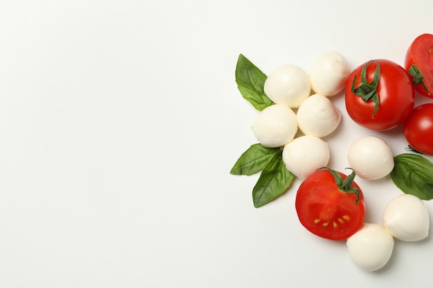 Mozzarella cheese, tomato and basil on white background, space for text