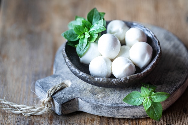 Mozzarellakaas, basilicum in een keramische kom op een houten bord.