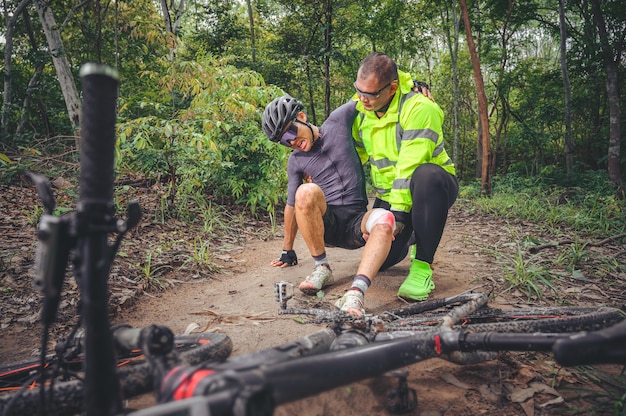 MTB mountain bike accident and first aid : Biker crash crashes, injuring knee and leg, First aid to help mountain biker in accident. Mountain bike athlete first aid team injured during race accident.