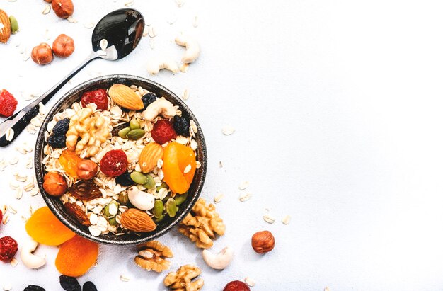 Muesli bowl organic ingredients for healthy breakfast Granola nuts dried fruits oatmeal whole grain flakes on white background Copy space banner