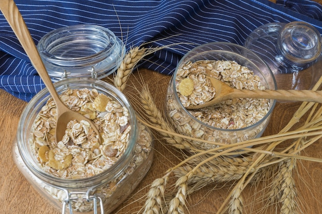 Photo muesli, breakfast cereal, oatmeal in a glass container on a wooden table. rustic food.