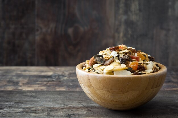 Muesli and dried fruit in wooden bowl on wooden table copy space