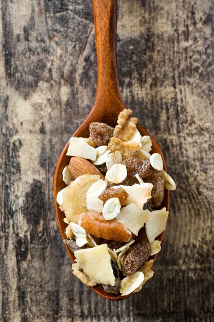 Photo muesli and dried fruit in wooden spoon on wooden table.