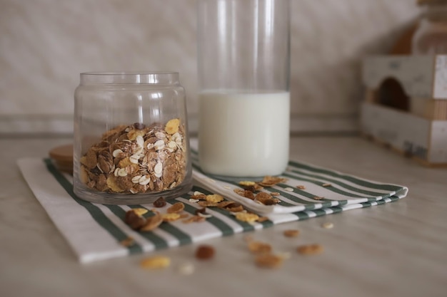 Muesli in een doorzichtige pot staat naast een fles melk op een tafel op een kunjontafel