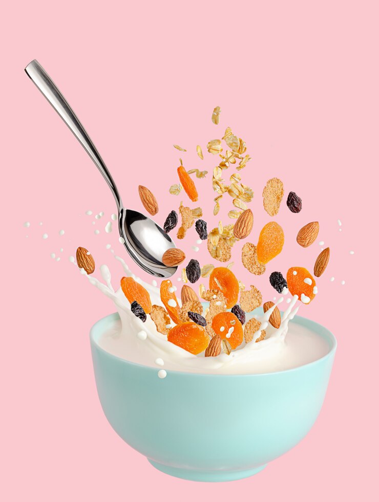 Muesli ingrediënten vliegen over kom met spatten melk. Geïsoleerd op roze muur.