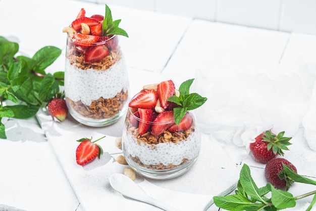 Muesli met chia yoghurt en aardbeien in een glas op een witte achtergrond