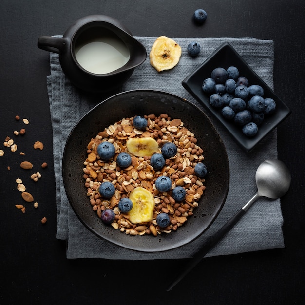 Muesli met melk geserveerd in kom op donkere achtergrond.