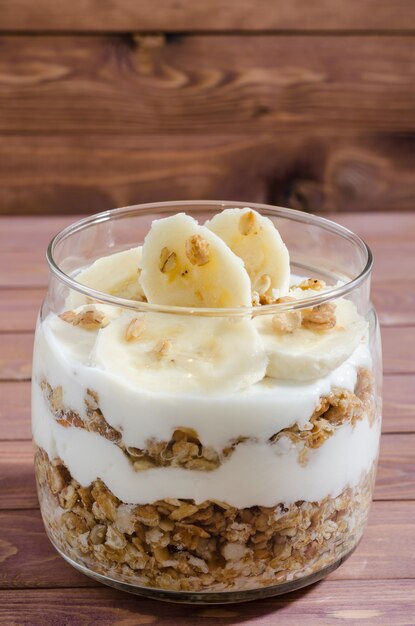 Muesli met natuurlijke yoghurt, banaan, noten en gedroogde vruchten in een glazen pot