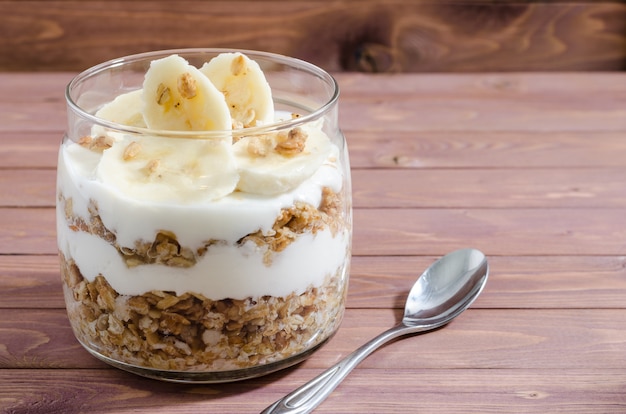 Muesli met natuurlijke yoghurt, banaan, noten en gedroogde vruchten in een glazen pot