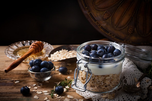 Muesli met yoghurt en blauwe bessen in glazen pot.