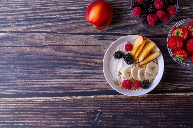 Muesli met yoghurt en fruit op een donkere houten tafel