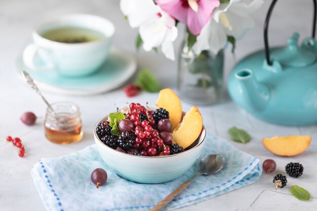 Muesli of muesli met bessen en fruit voor een gezond ontbijt in de ochtend met een boeket zomerbloemen op een lichte tafel.