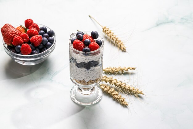 Muesli with berries and chia seeds on a light marble table