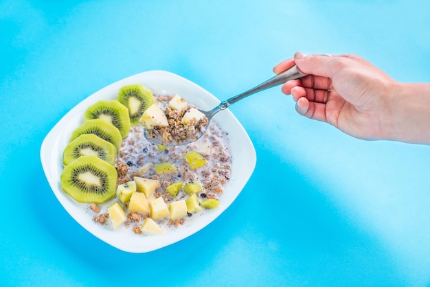 muesli with kiwi and apple with milk on a blue background