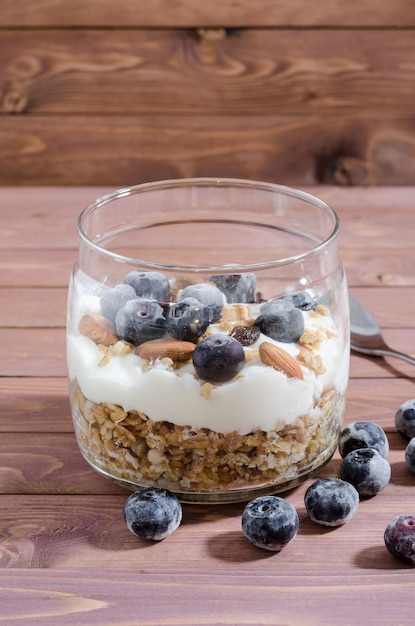 Muesli with natural yoghurt, blueberry, nuts and dried fruits in a glass jar