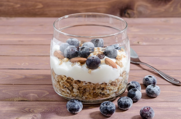 Muesli con yogurt naturale, mirtillo, frutta secca e frutta secca in un barattolo di vetro